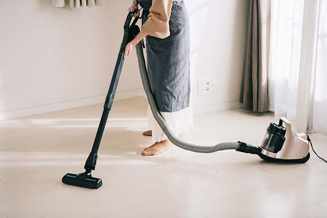 床の掃除機をかける女性