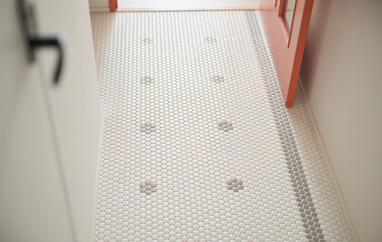 三和土と廊下には丸いモザイクタイルが。オレンジ色の室内扉の奥にLDKが広がっています