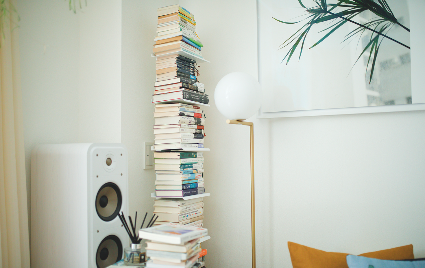 ソファの横にうず高く積まれた本の大半は文芸書。フロアランプは「FLOS（フロス）」のもの