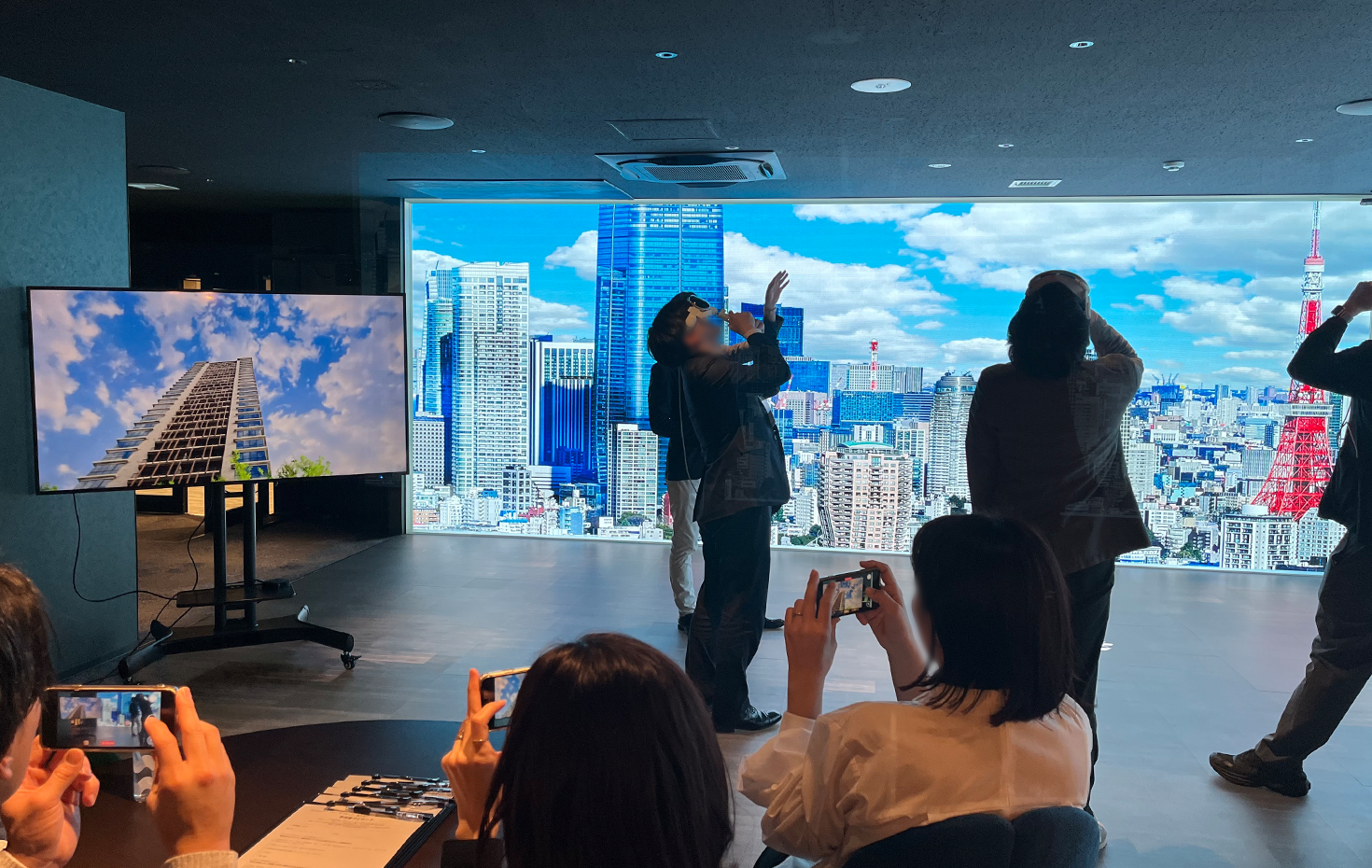 Apple Vision Proを装着すると、視界には仮想空間が広がり、マンションを地上から眺めるようなイメージが見える。左モニターにはApple Vision Proで見えているイメージが映る