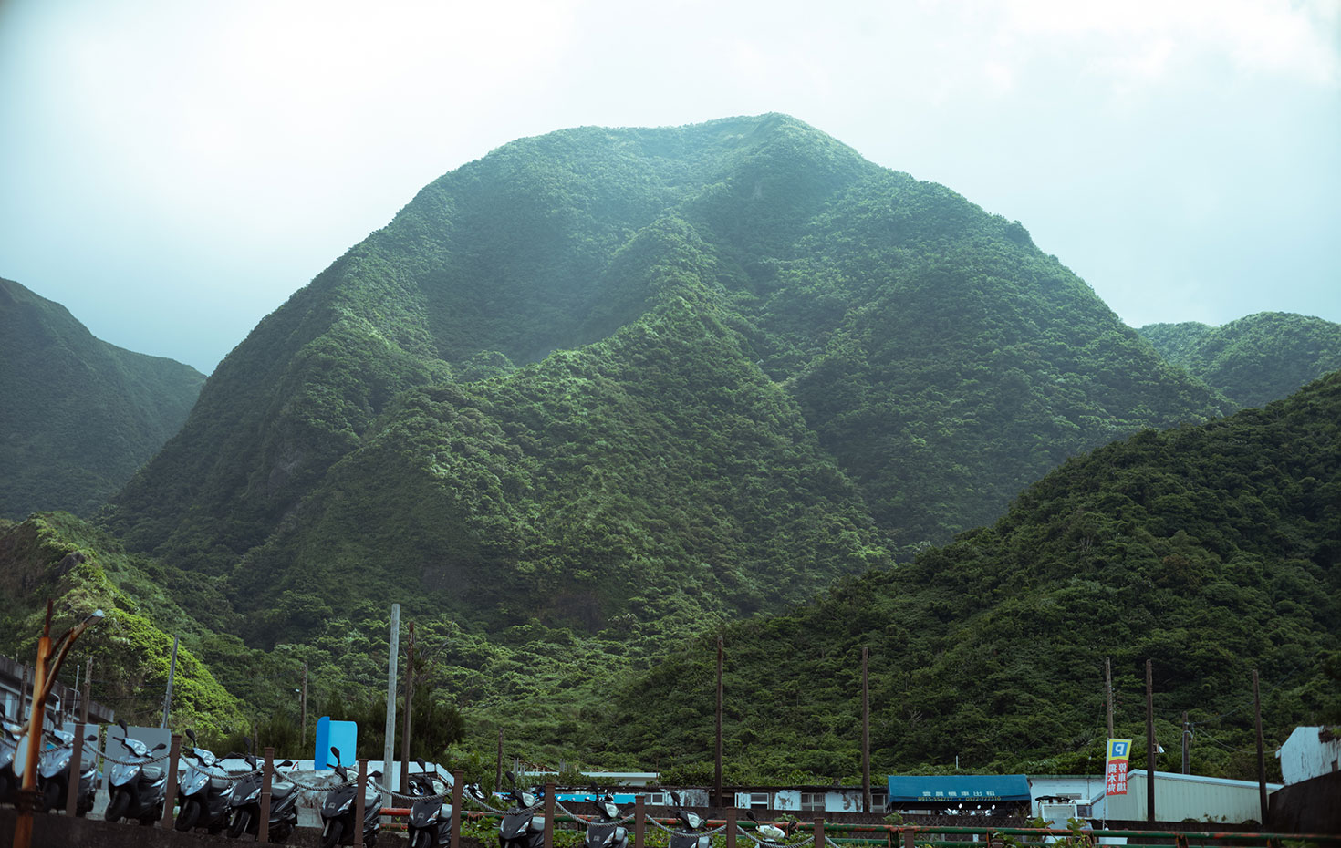 蘭嶼の玄関口、開元港の背後に迫る山々 港から道ひとつ挟んでそびえる山を見上げながら、なかなか現れないガイドの周さんを待つ。